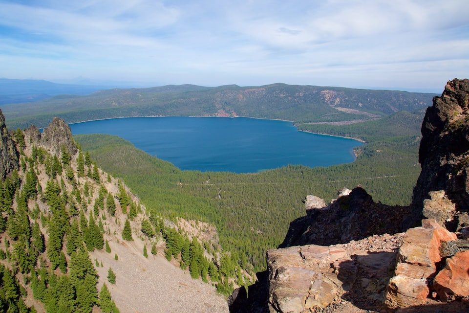 A mountainous landscape with a lake surrounded by dense forests and rocky outcrops.