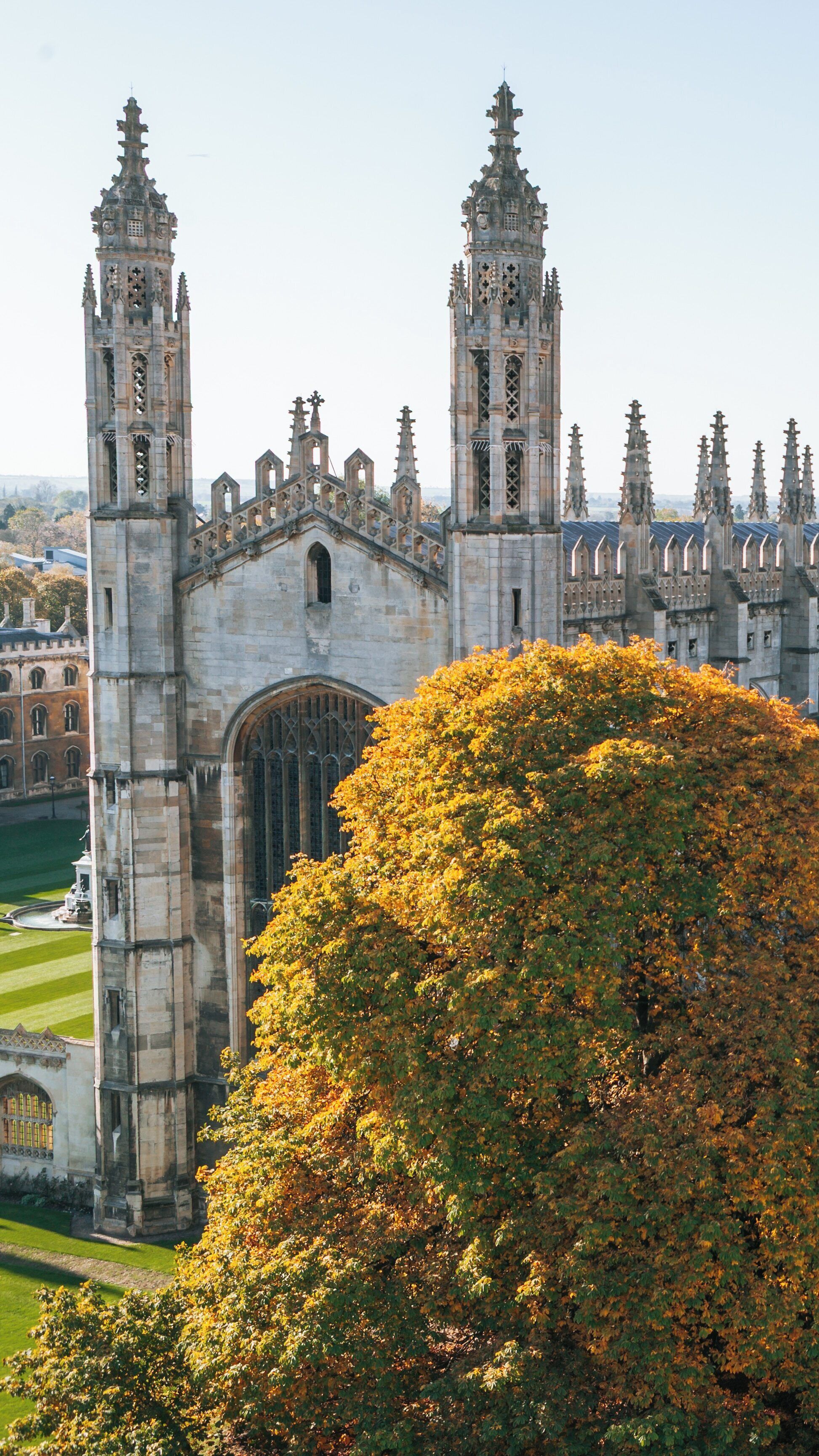 King's College Chapel stands majestically surrounded by autumn foliage in Cambridge, England during a clear and sunny day