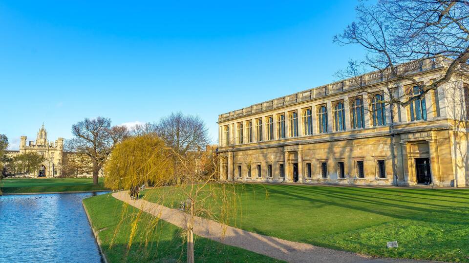 A historic building with large windows and a river in the foreground.