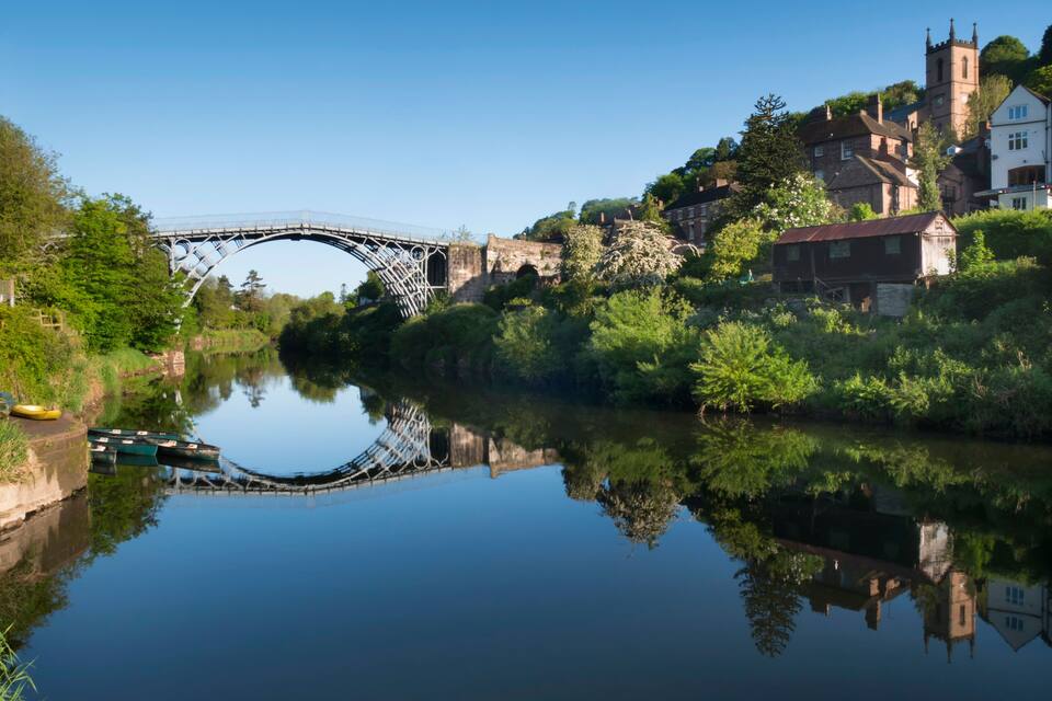 A river with a bridge, houses, and a church.