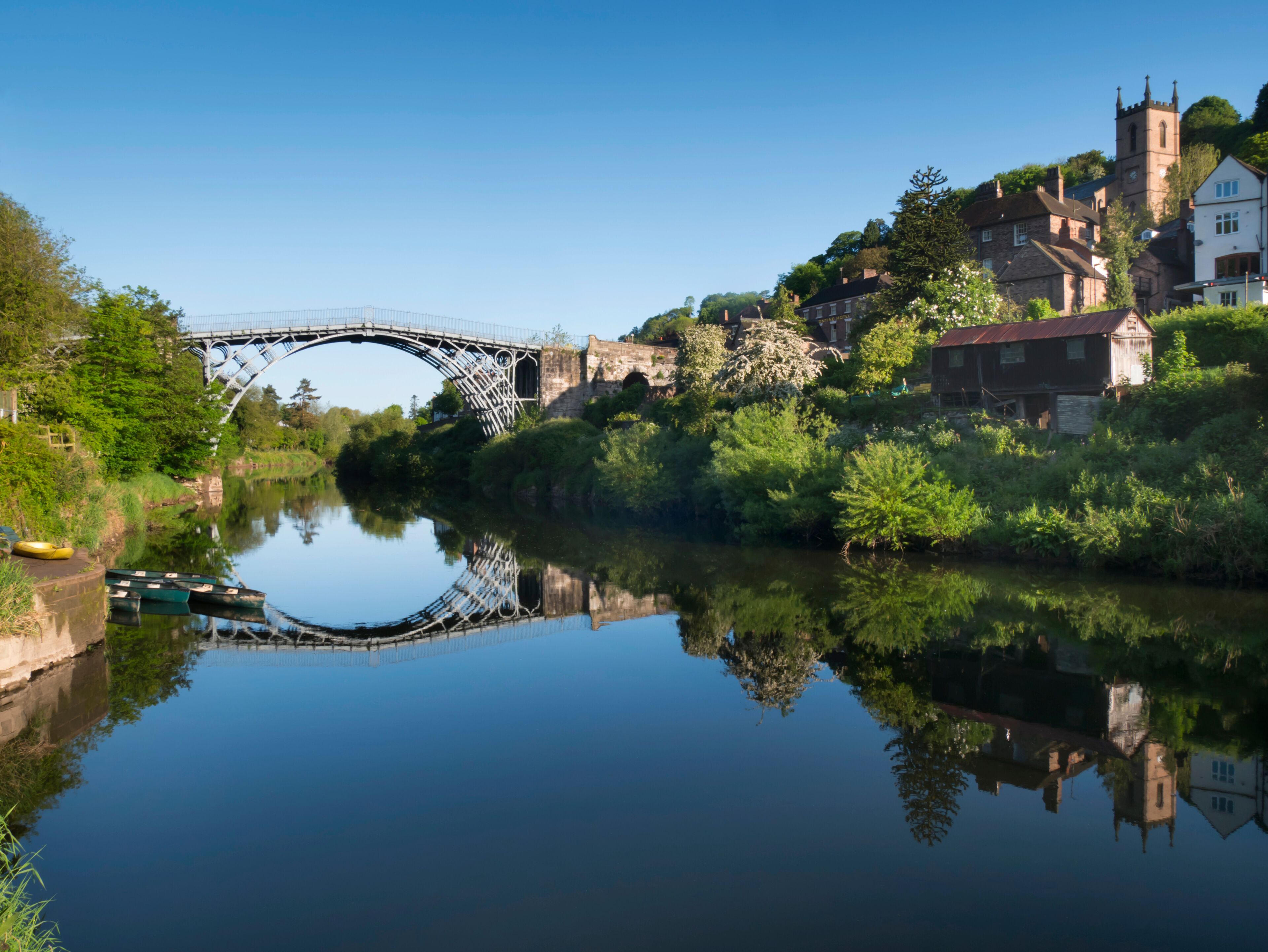 A river with a bridge, houses, and a church.