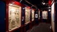A museum corridor with glass display cases containing porcelain and ceramic items.