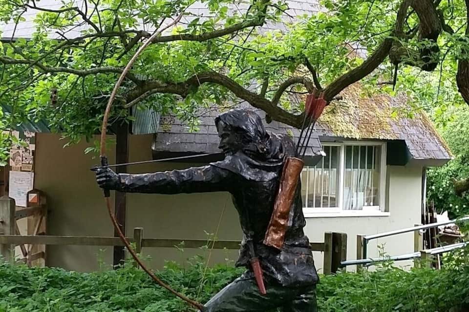 A statue of a figure with a bow and arrow in a garden.