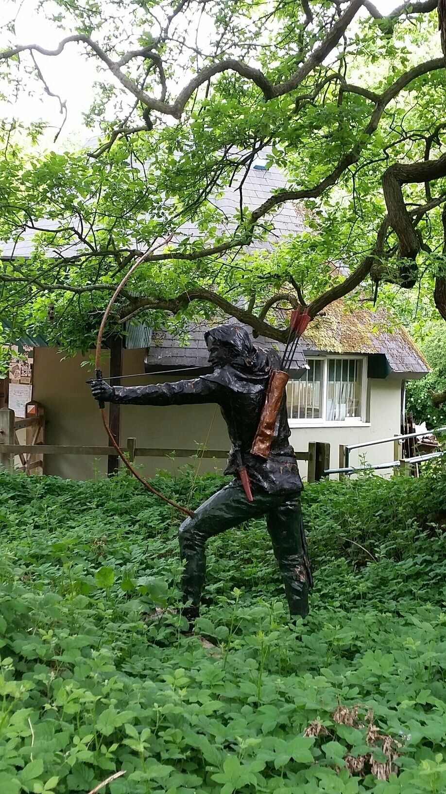 A statue of a figure with a bow and arrow in a garden.