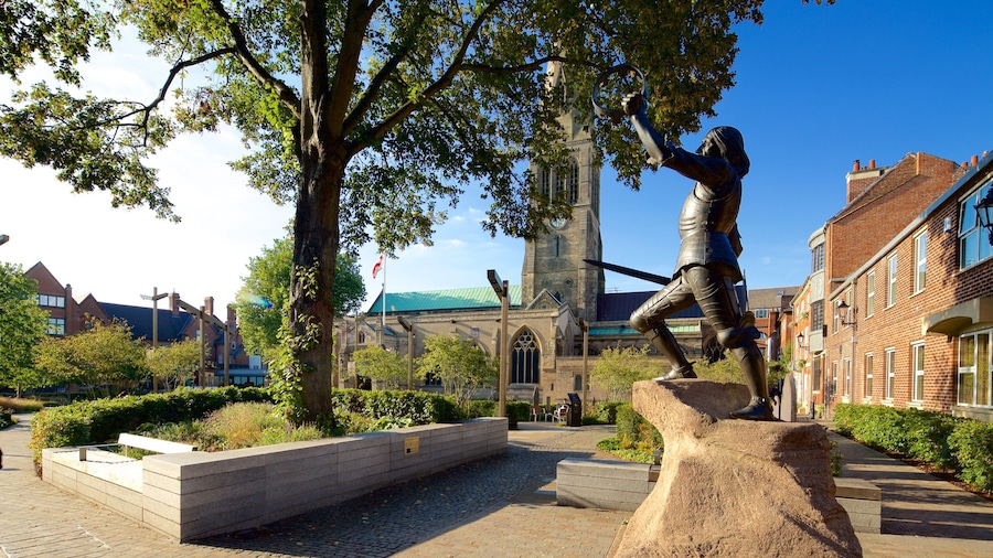 A statue of a knight in armor, a church with a green roof, and traditional brick buildings.