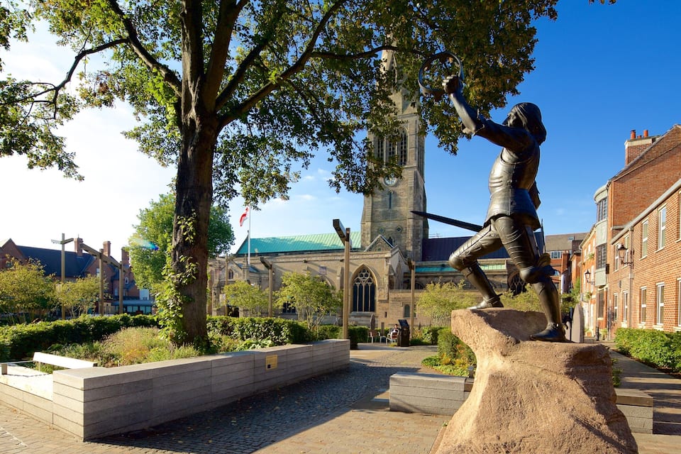 A statue of a knight in armor, a church with a green roof, and traditional brick buildings.