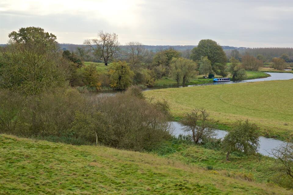 A river winding through a green landscape with trees and a boat in the distance.