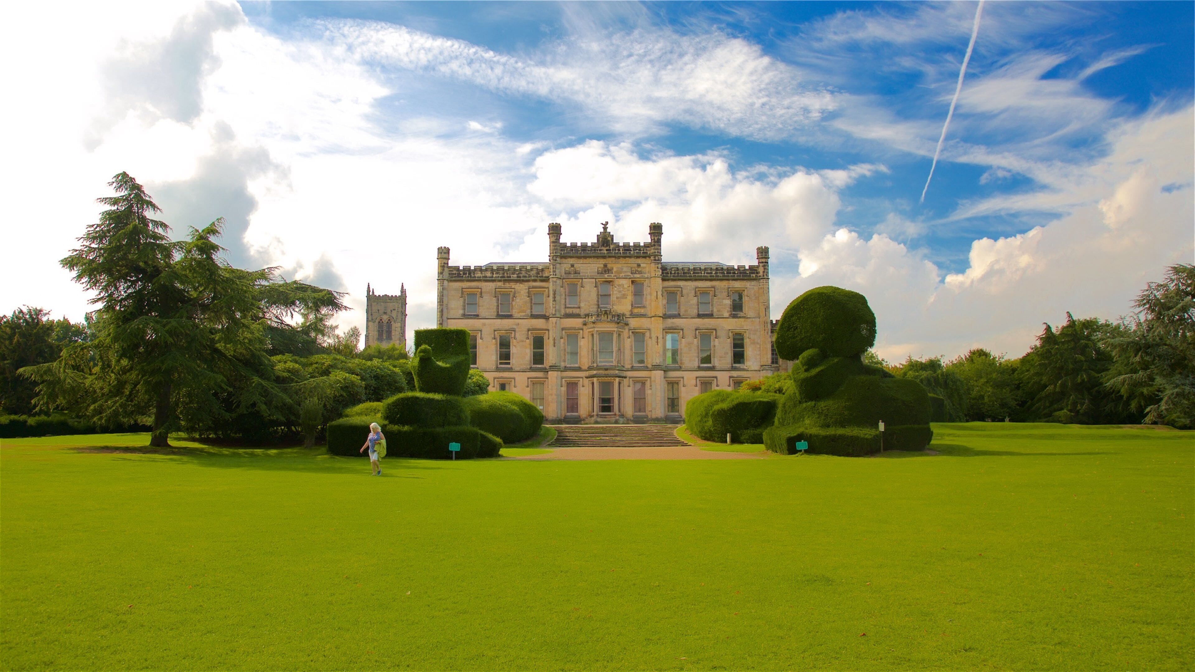 A large, historic building with a symmetrical facade, surrounded by well-manicured lawns and trees.