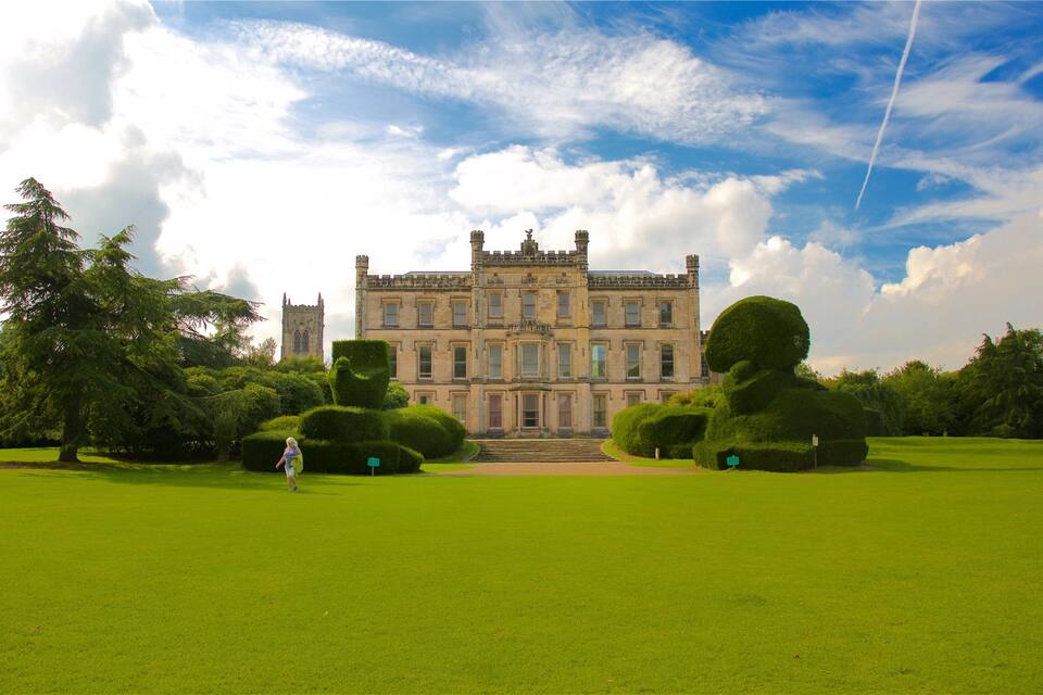 A large, historic building with a symmetrical facade, surrounded by well-manicured lawns and trees.