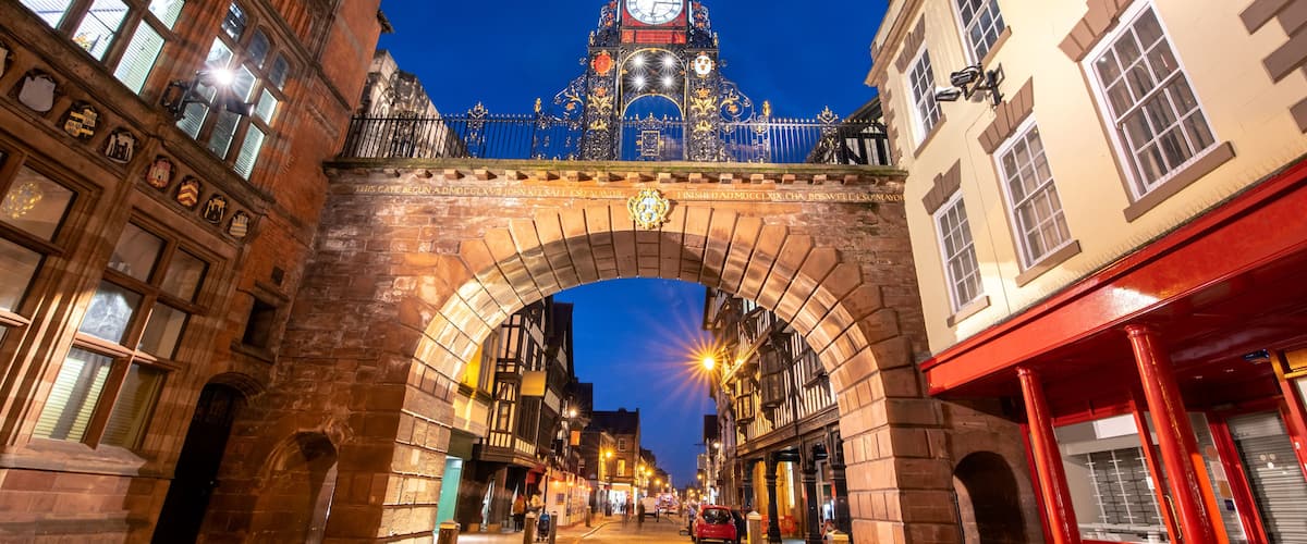 A historic street with an ornate clock tower, cobblestone pavement, and traditional architecture.