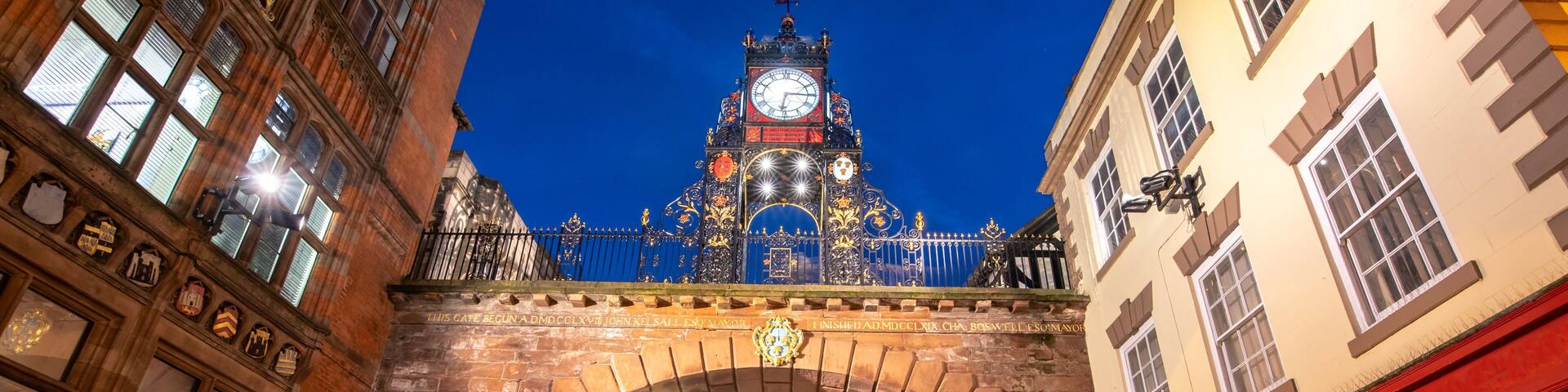 A historic street with an ornate clock tower, cobblestone pavement, and traditional architecture.