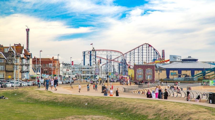 A seaside amusement park with roller coasters and a Ferris wheel.