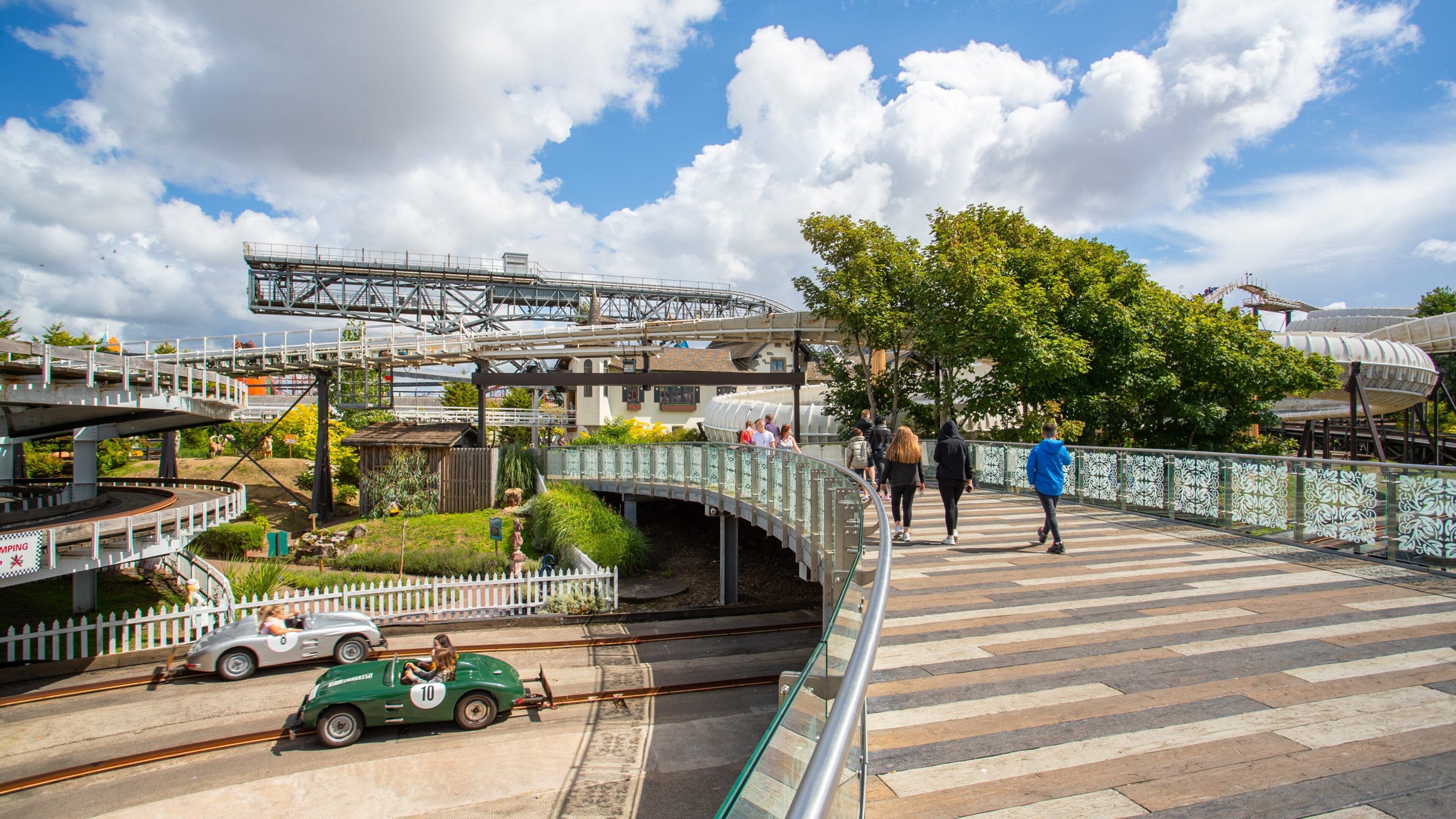 A model train track with a green car, a bridge, and a tree.