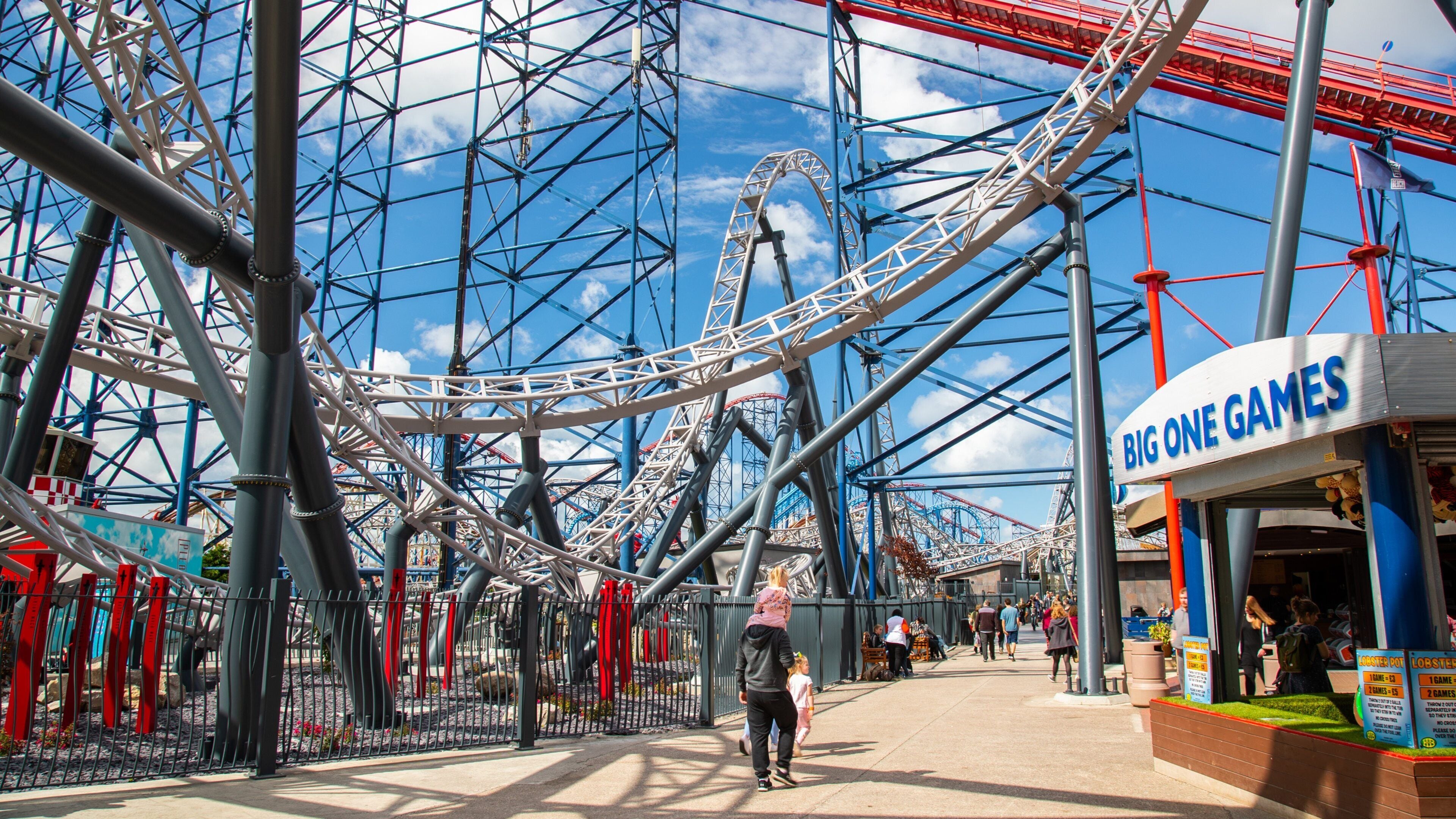 Una montaña rusa con una noria de fondo y un salón recreativo 'Big One Games'.