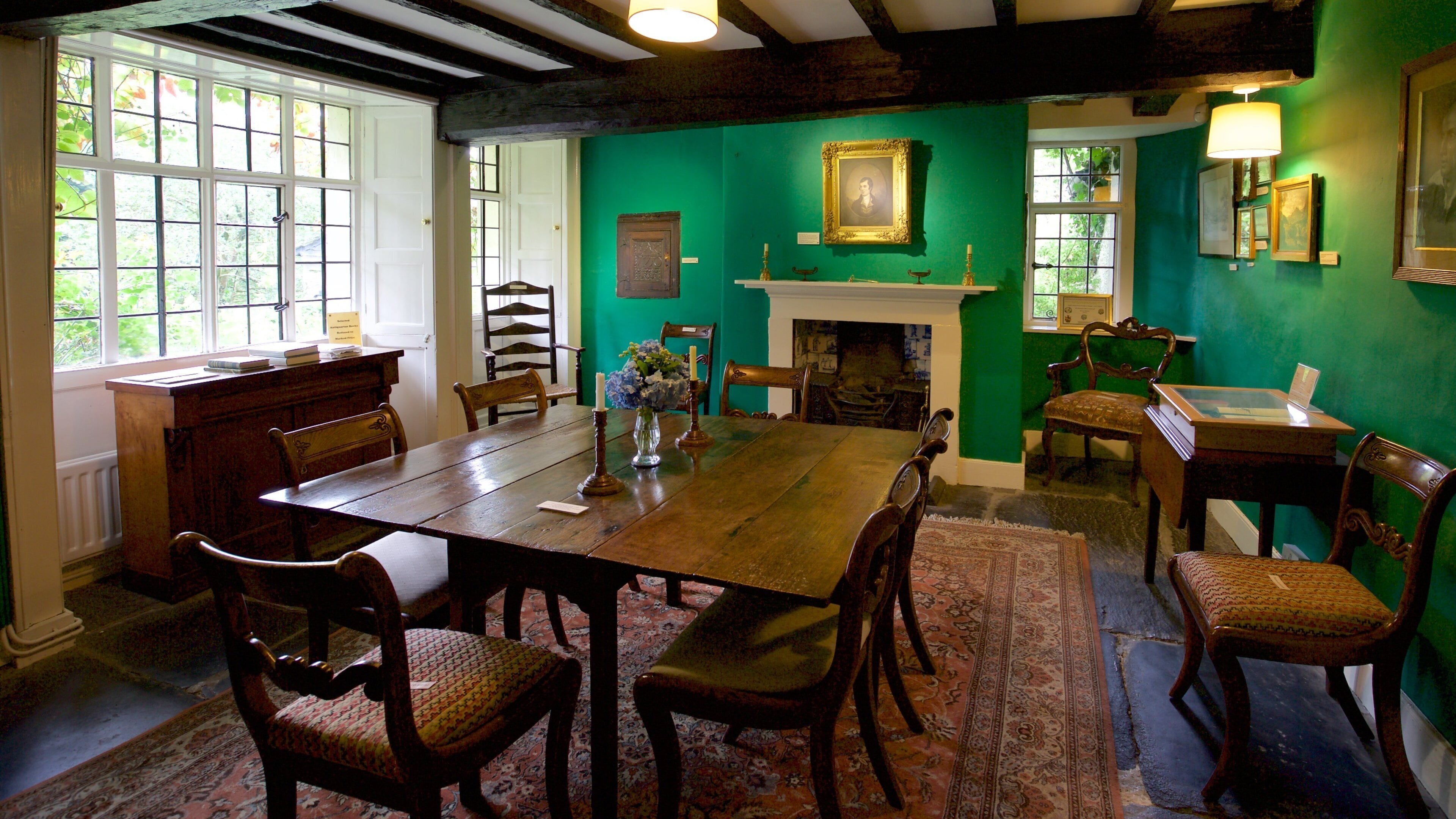 A traditional dining room with a wooden table, chairs, and a green wall.
