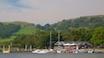 A marina with boats docked, a wooden pier, and a building with a sloped roof.