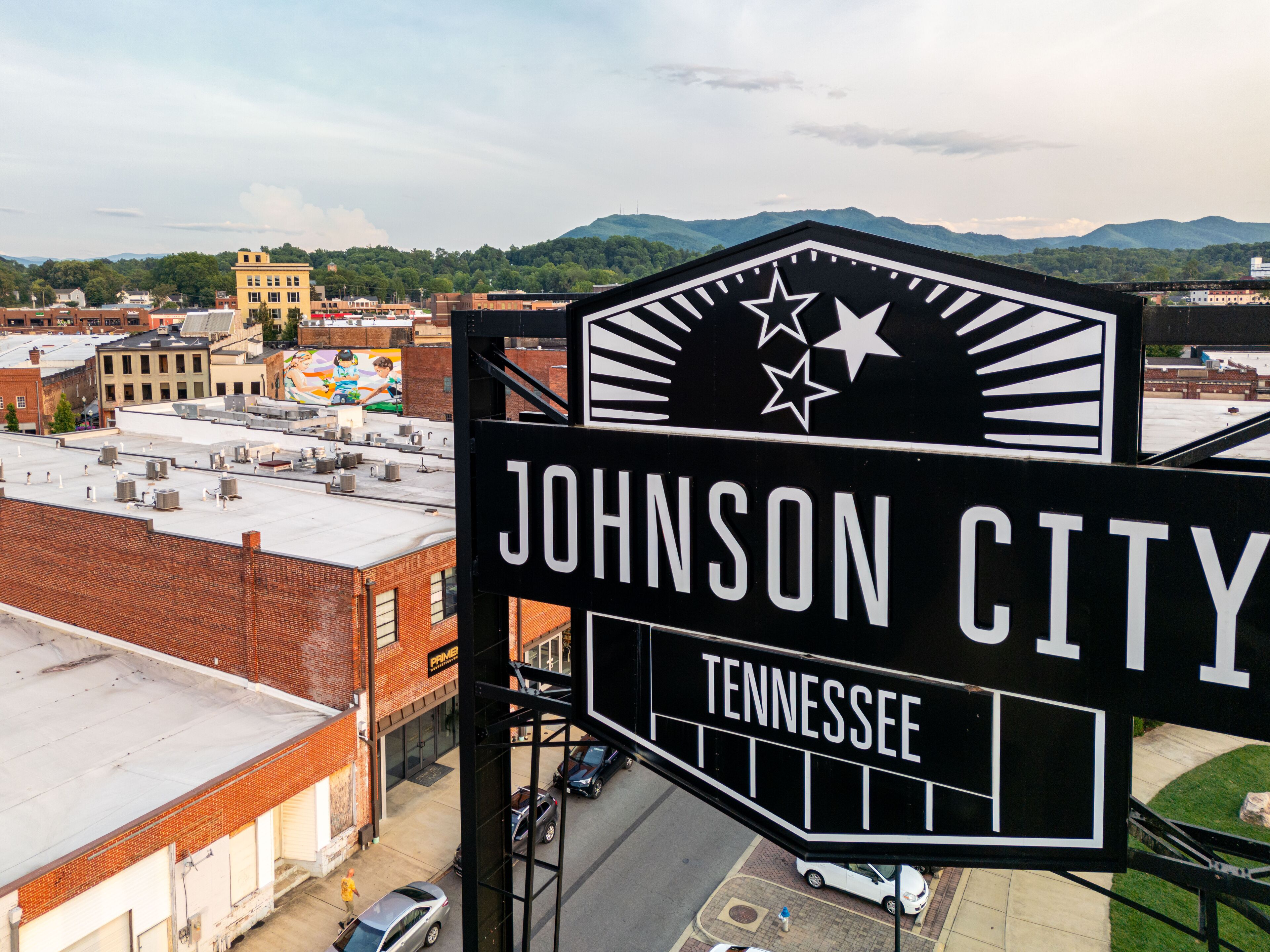 A sign for Johnson City, Tennessee, with a view of the cityscape and mountains in the background.