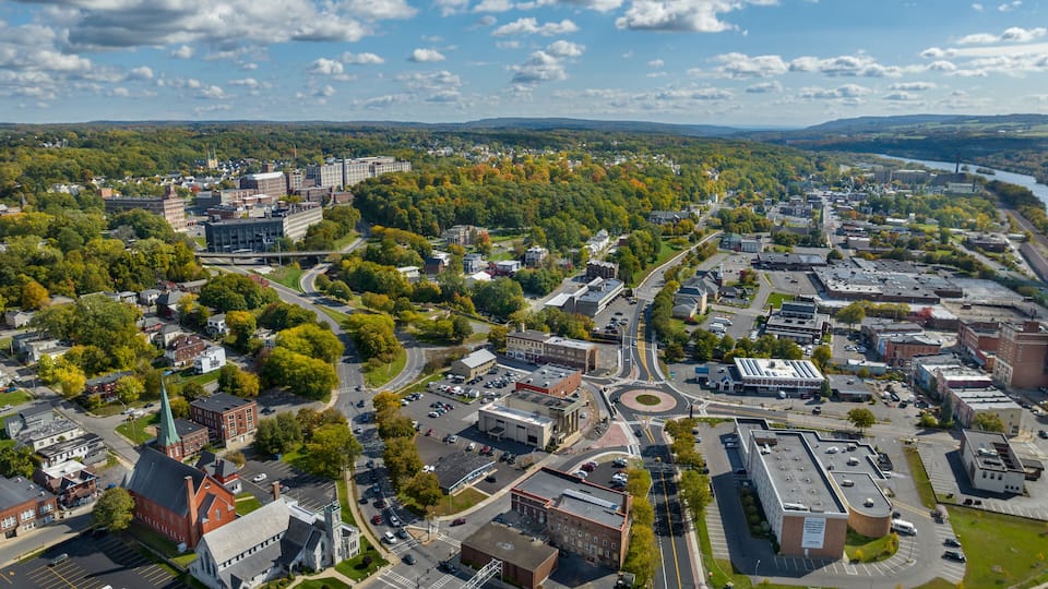 An aerial view of a city with a mix of green parks, buildings, and a river.