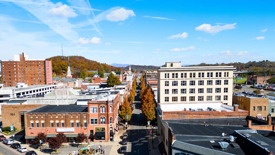 A city street lined with historic buildings, a prominent church steeple, and a clear blue sky.