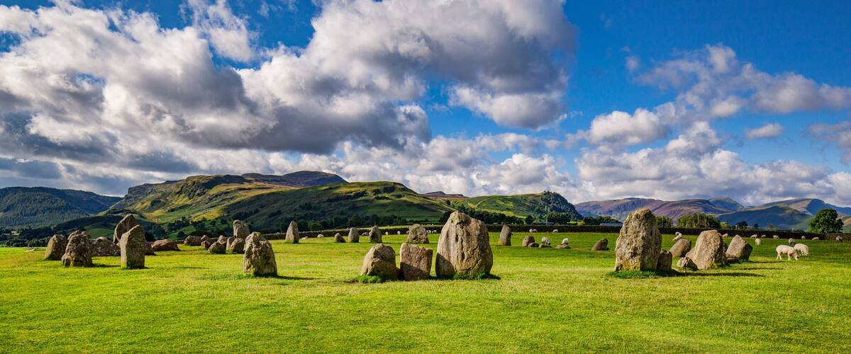 A stone circle landscape with rolling hills and a clear blue sky.