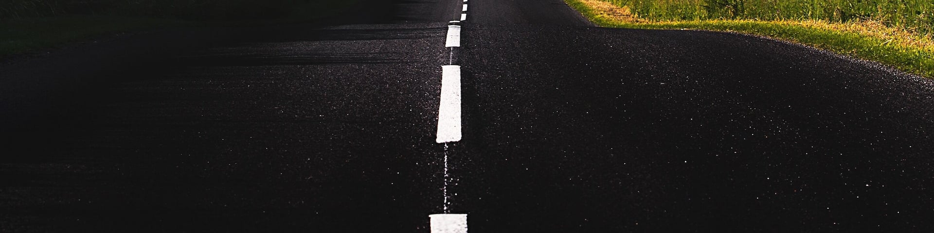 A straight road leading towards a mountain range with a clear sky.