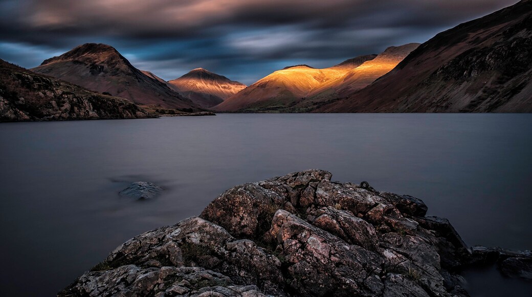 After traveling for an hour from our hotel hoping that we would not miss the sunset we arrived at our destination and quickly setup and waited for the sun to disappear to the righthand side of the rolling hills in the Lake District and when it did we started shooting long exposures of around 60 seconds so that it would smooth the water out and get movement in the dark moody sky above and finally after about 10 minutes the sun hit the hills in the distance and what a site it was