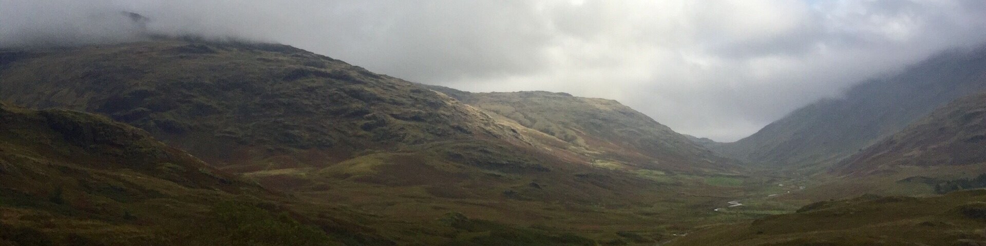 A winding road through a mountainous landscape with a cloudy sky.