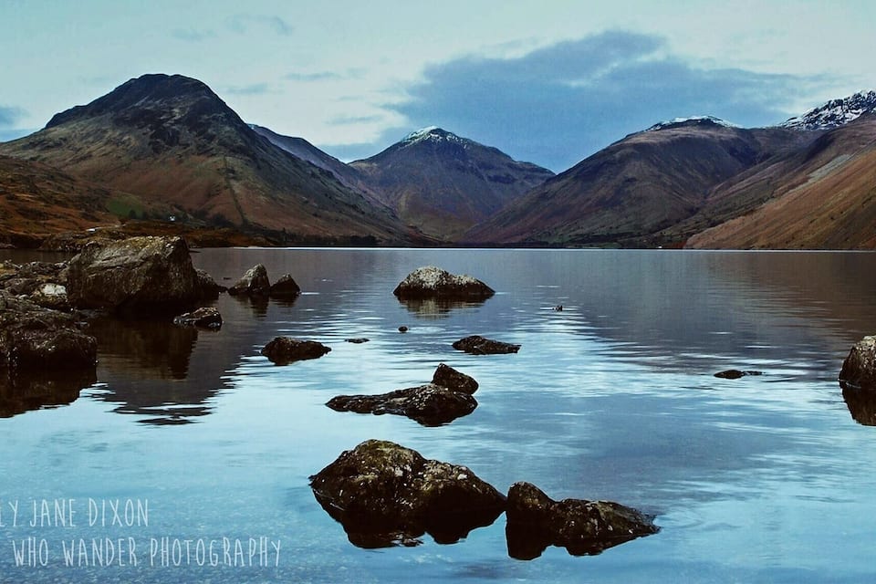 A calm lake surrounded by mountains with rocky shores.