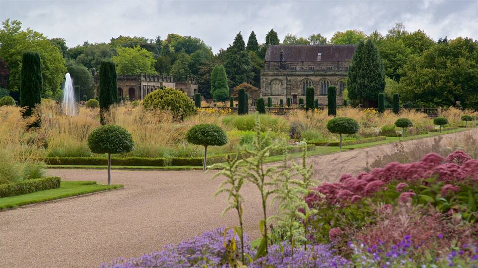 A formal garden with a gravel path, neatly trimmed hedges, and a variety of flowering plants.