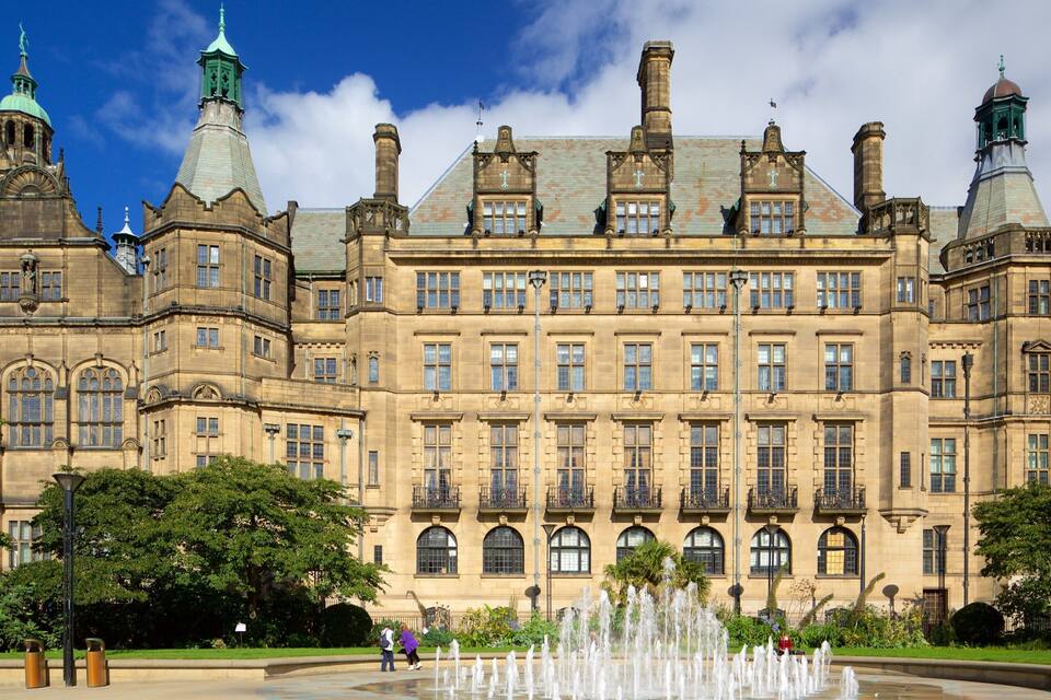 A historic building with multiple towers and a fountain in the foreground.