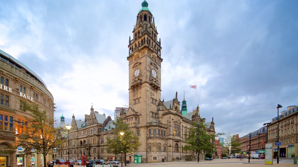 A historic building with a clock tower, surrounded by modern buildings and a clear sky.