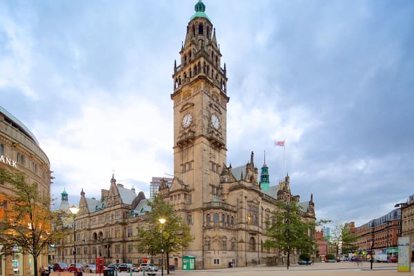 A historic building with a clock tower, surrounded by modern buildings and a clear sky.