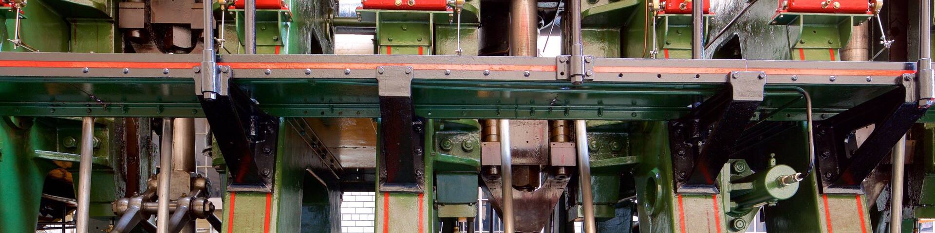 A complex industrial machine with green and red components, featuring multiple pipes and mechanical parts.