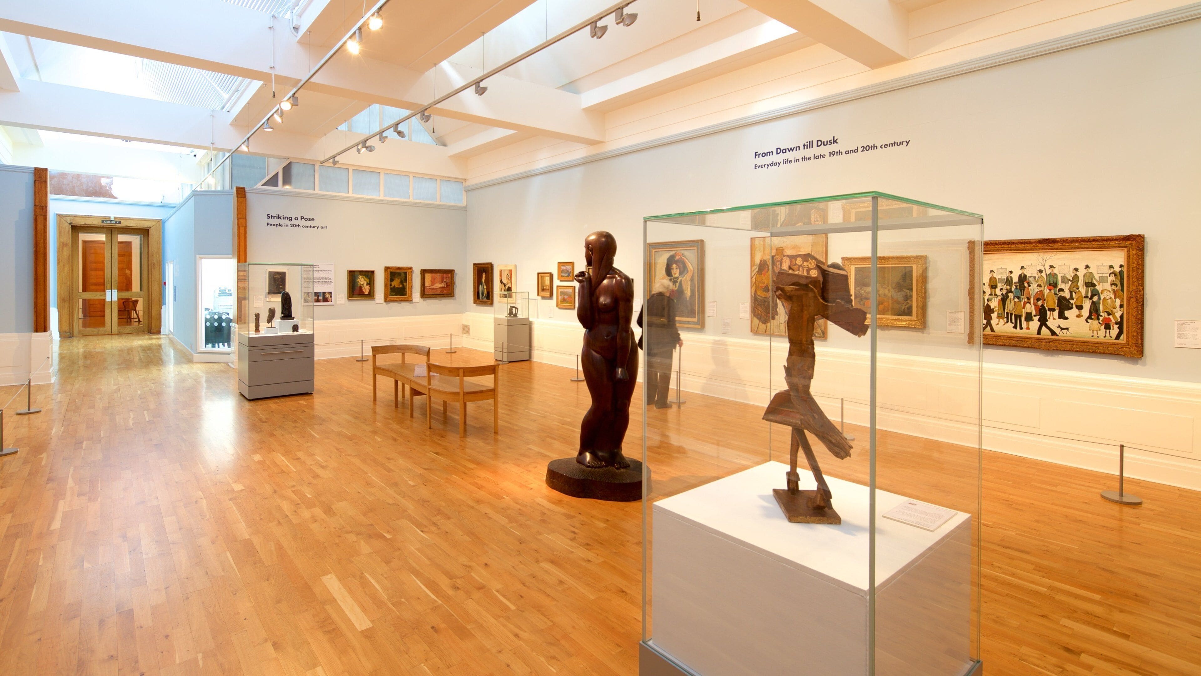 Una galleria d'arte con pavimenti in legno, vetrine in vetro e diverse opere pittoriche.