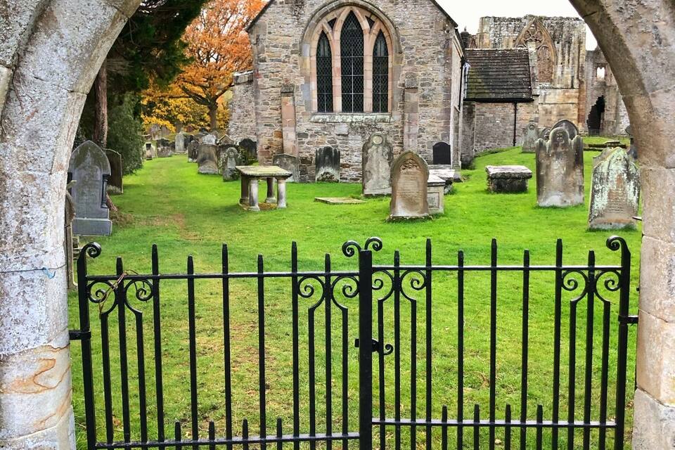 A church with a stone archway and a cemetery in the background.