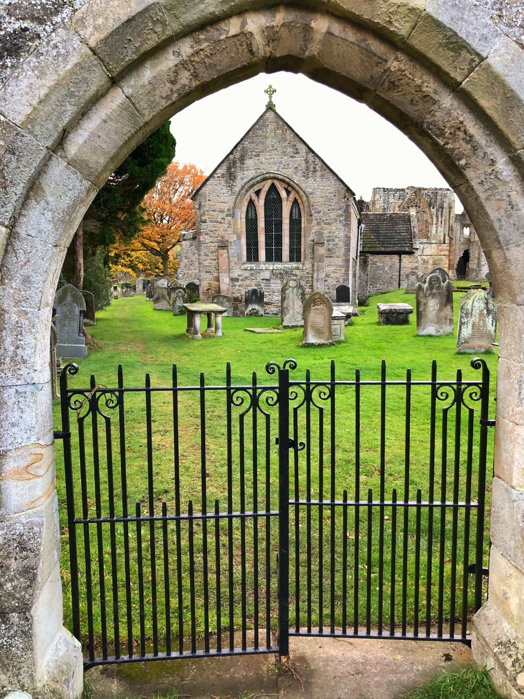 A church with a stone archway and a cemetery in the background.