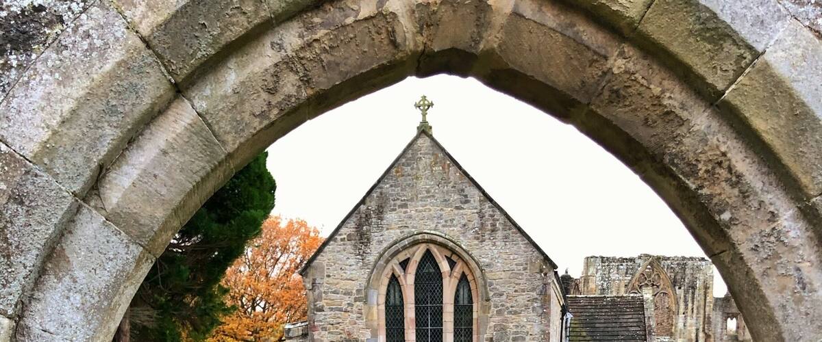 A church with a stone archway and a cemetery in the background.