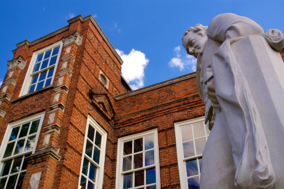 A red brick building with white windows and a statue of a man.