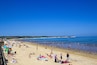 A crowded beach with people sunbathing and swimming.