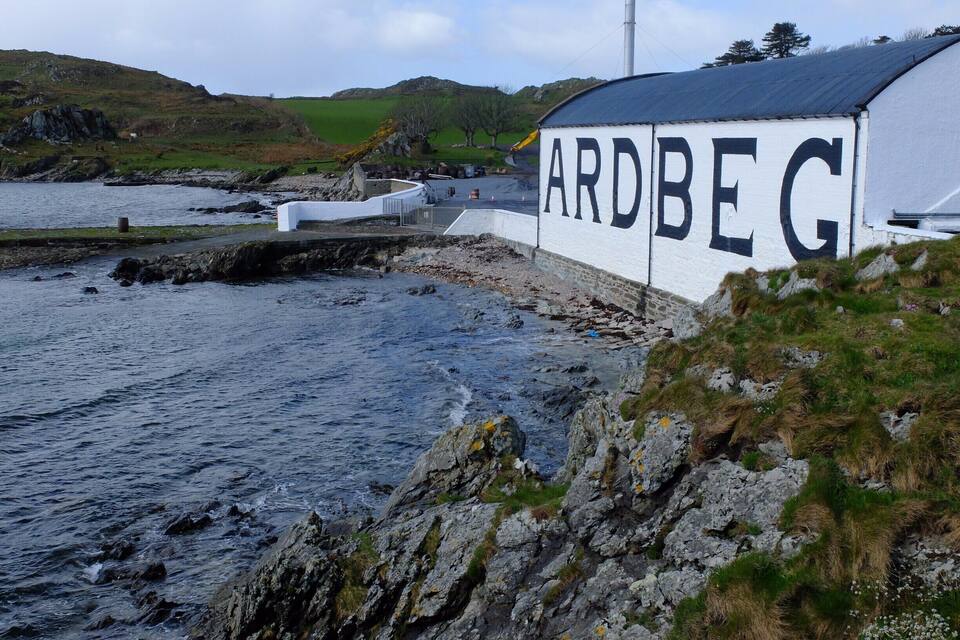 Een kustlandschap met een gebouw, waarop 'ARDBEG' staat.