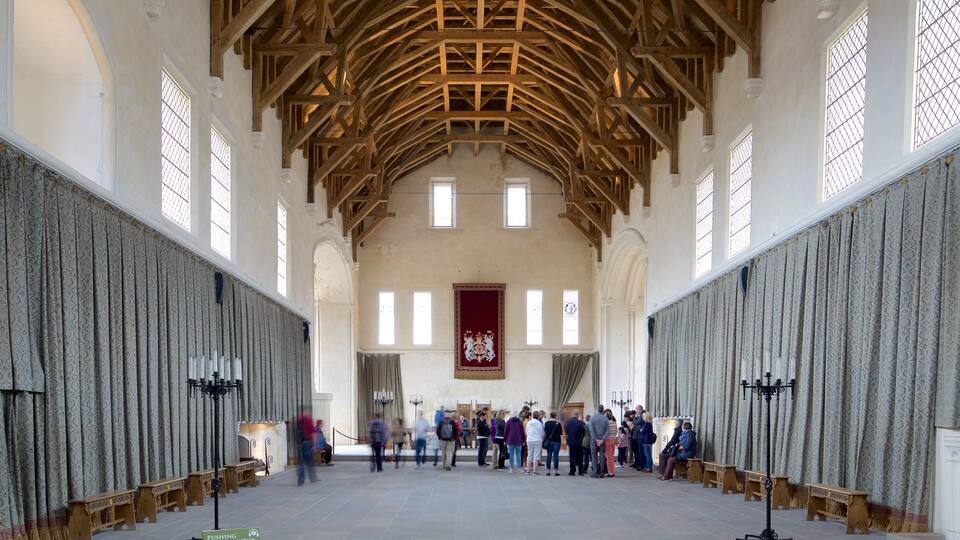 A large hall with high wooden beams, patterned curtains, and a red banner.