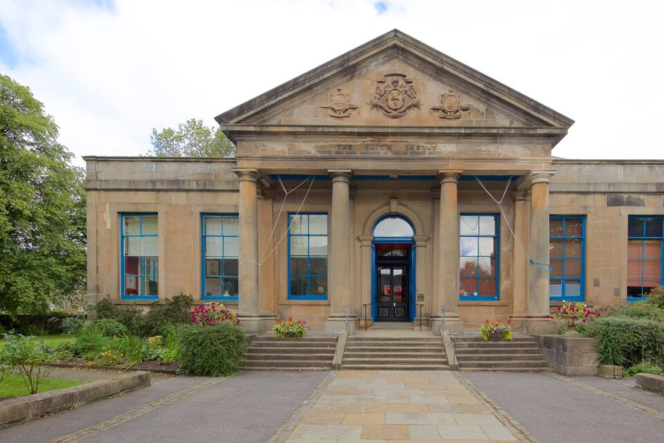 A historic building with a prominent entrance, large windows, and a central archway.