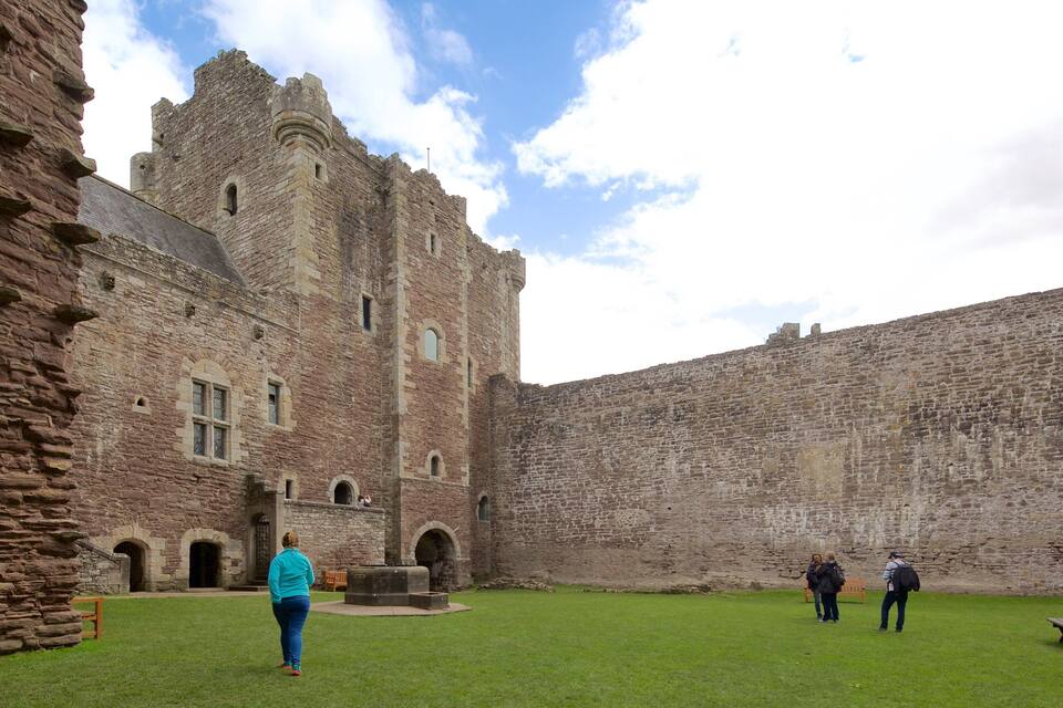 A historic stone castle with a large courtyard, a central tower, and a surrounding high wall.