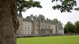 A historic castle with multiple towers and a well-maintained lawn.