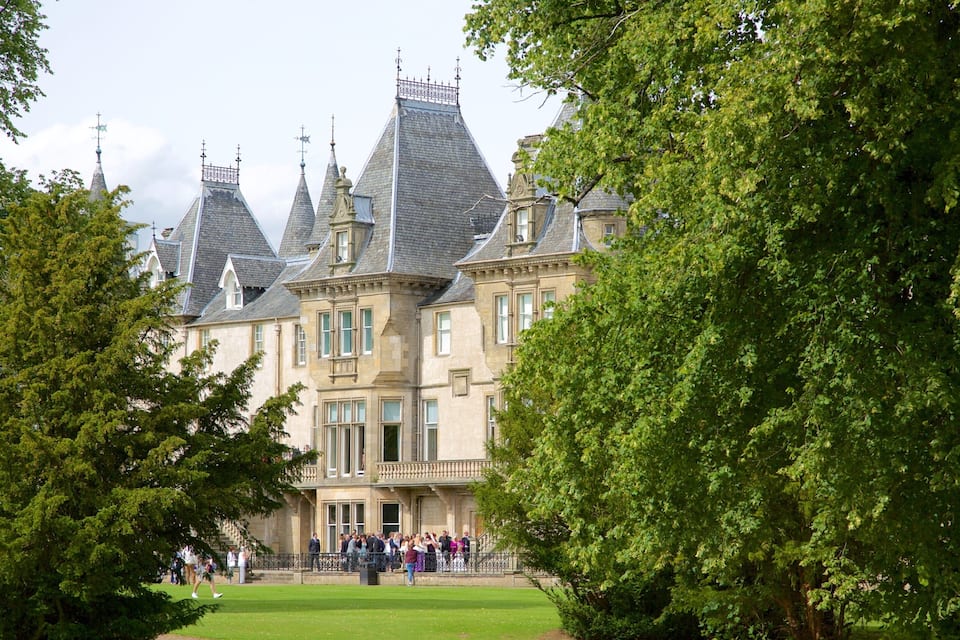 A historic building with multiple towers and a well-maintained lawn.
