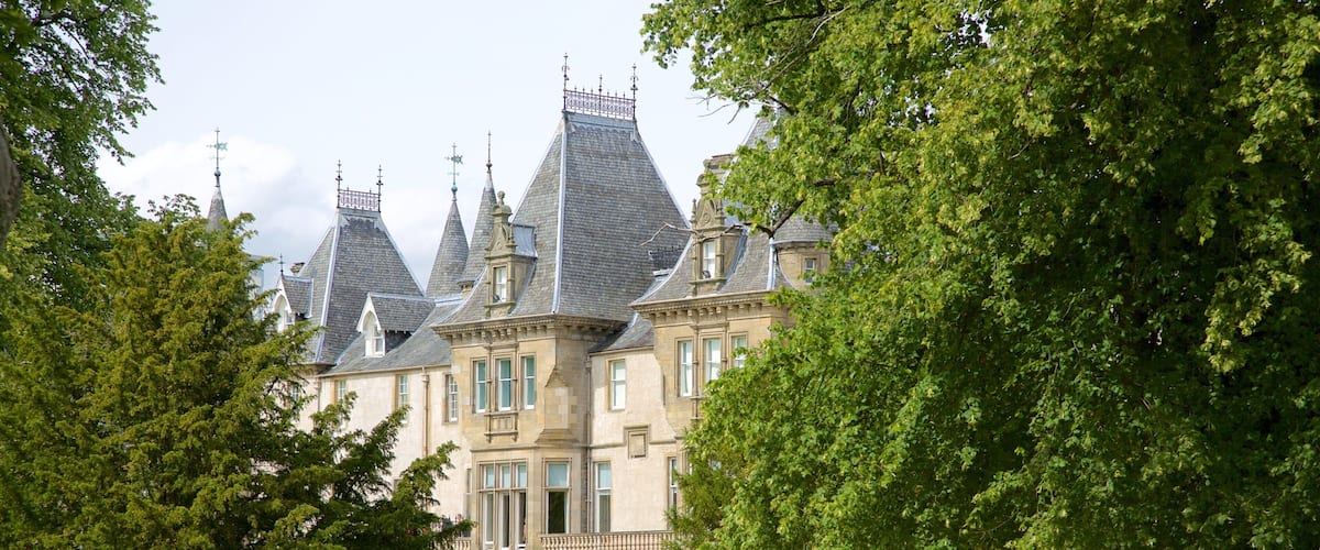 A historic building with multiple towers and a well-maintained lawn.