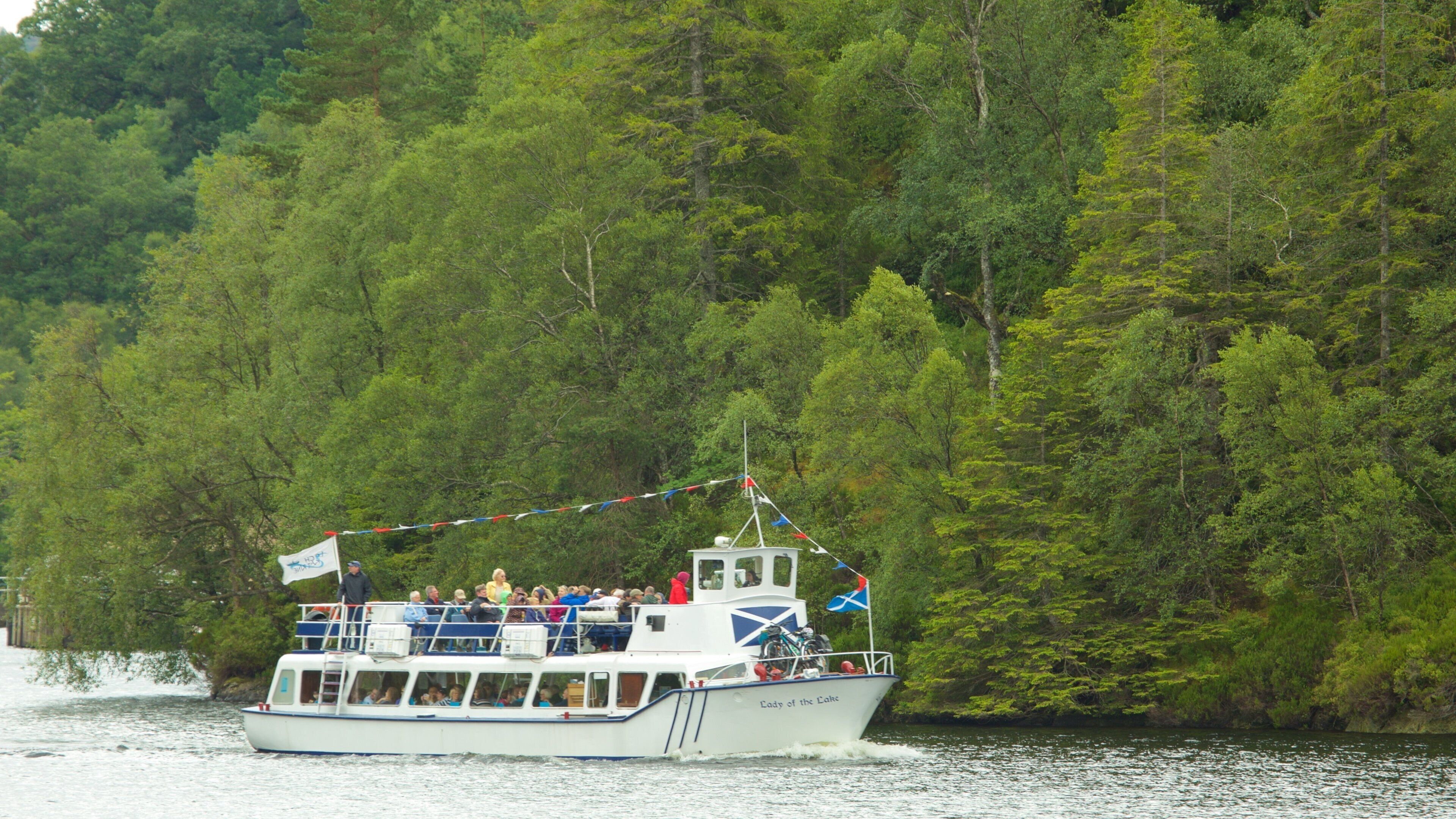 A boat named "Lady of the Lakes" on a river surrounded by dense green forest.