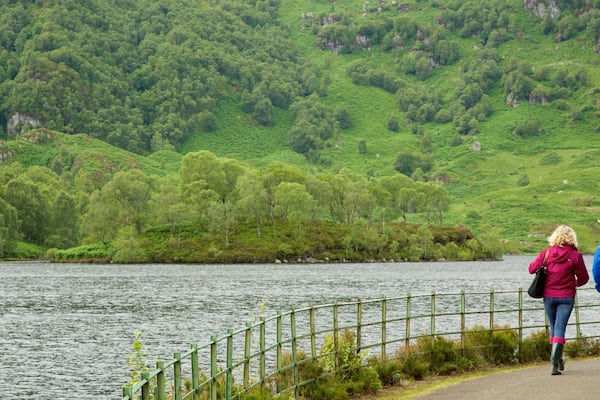 Loch Katrine das einen See oder Wasserstelle und Wälder sowie kleine Menschengruppe