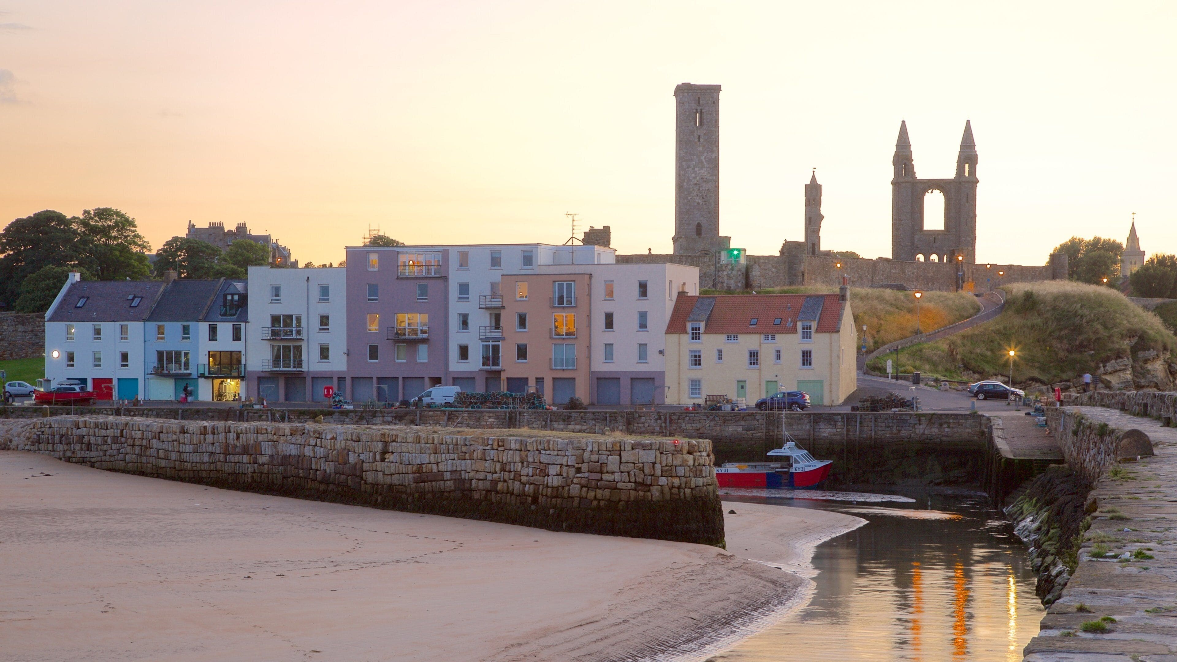 St. Andrew\'s Cathedral som viser solnedgang, kystby og sandstrand