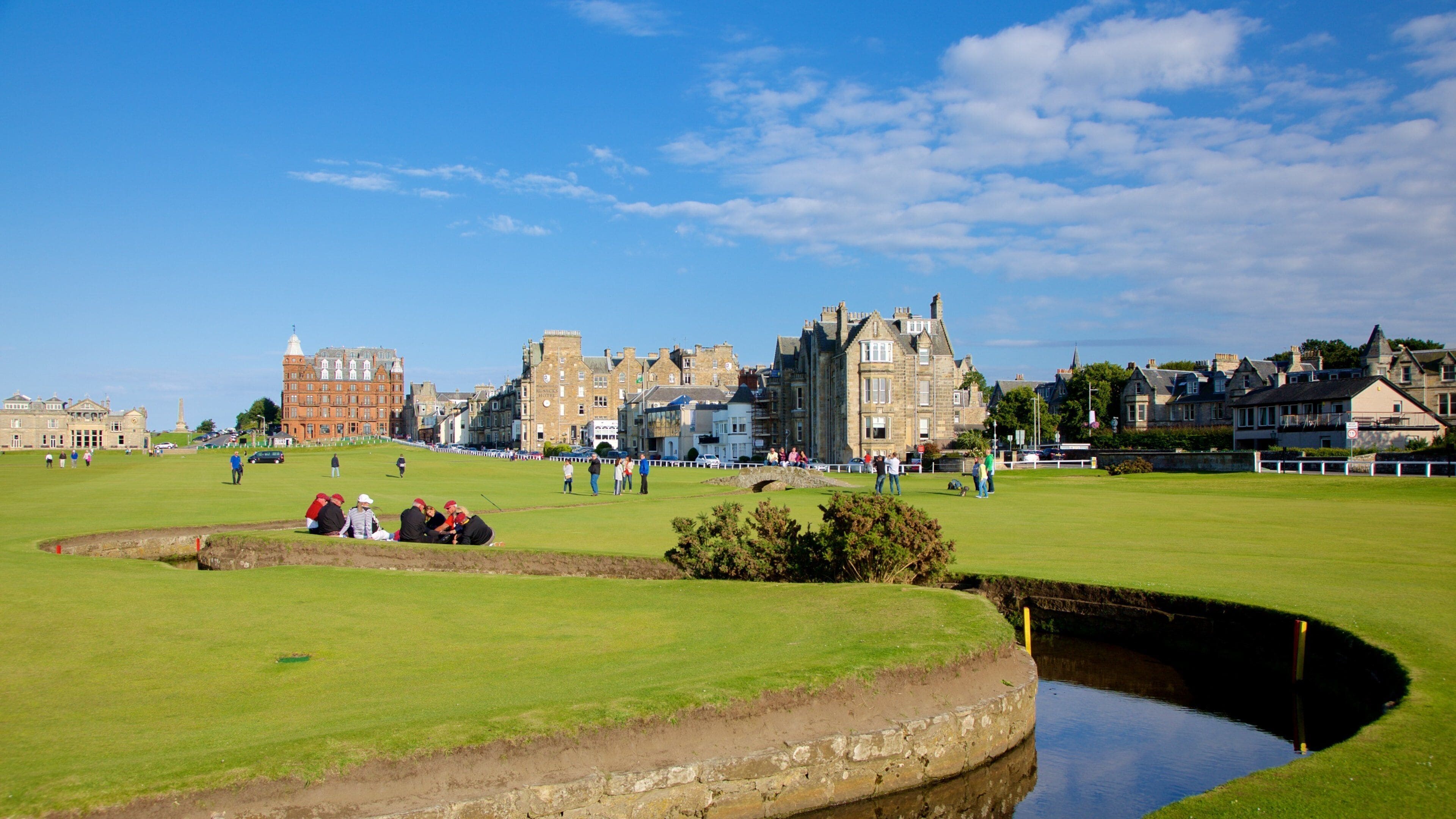 Un parcours de golf avec des bâtiments historiques en arrière-plan.